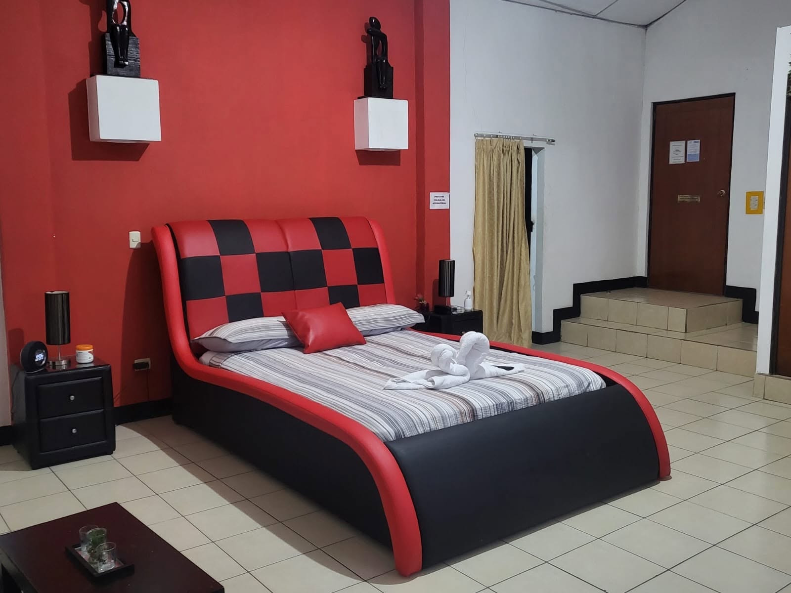 Ejecutivo, habitación 19: cama roja y negra con toallas en forma de cisnes